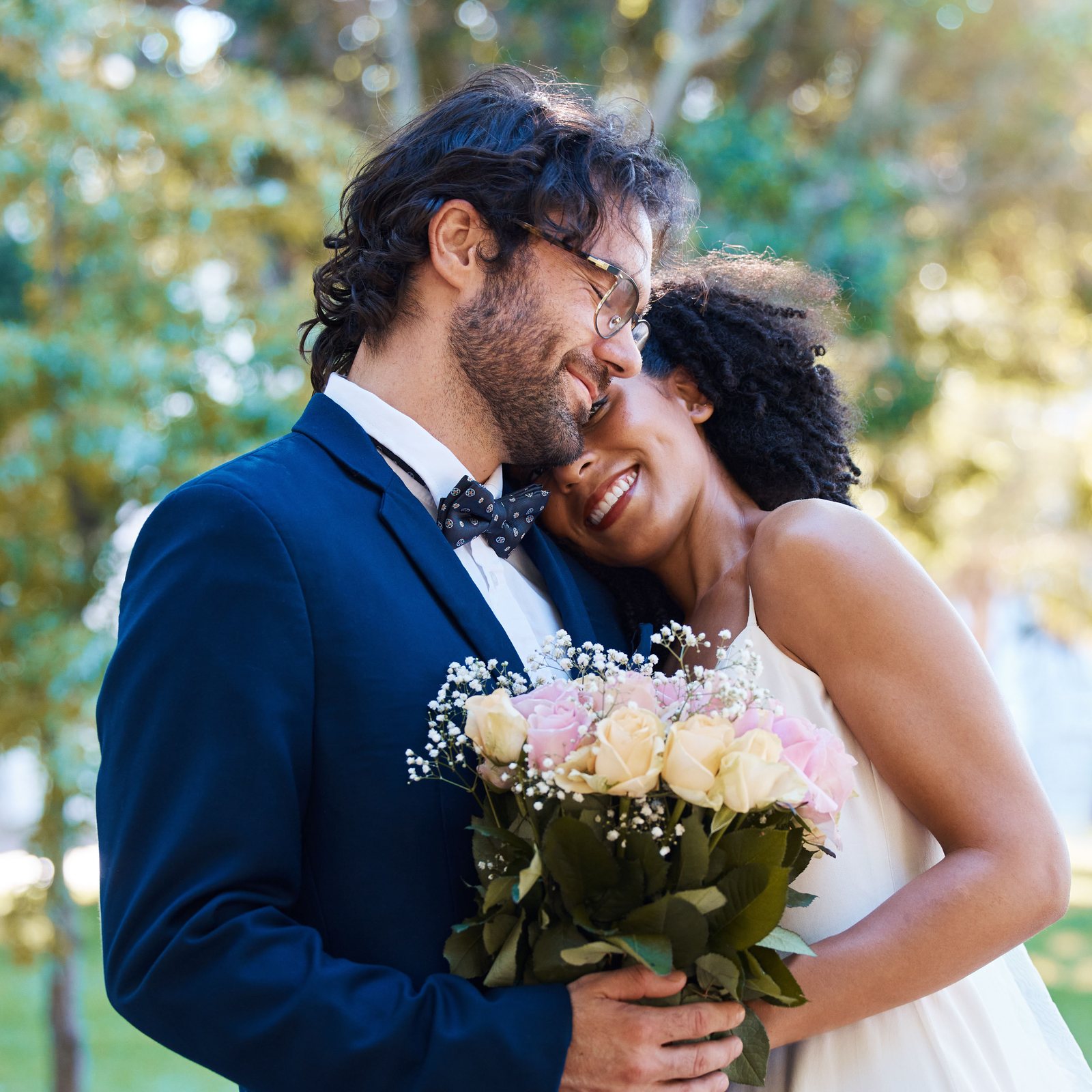 Groom in a navy suit hugging his smiling bride in golden late-afternoon light