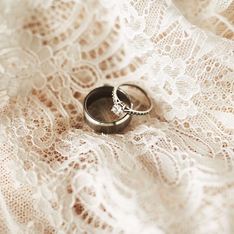 Wedding rings resting on the lace of a wedding gown