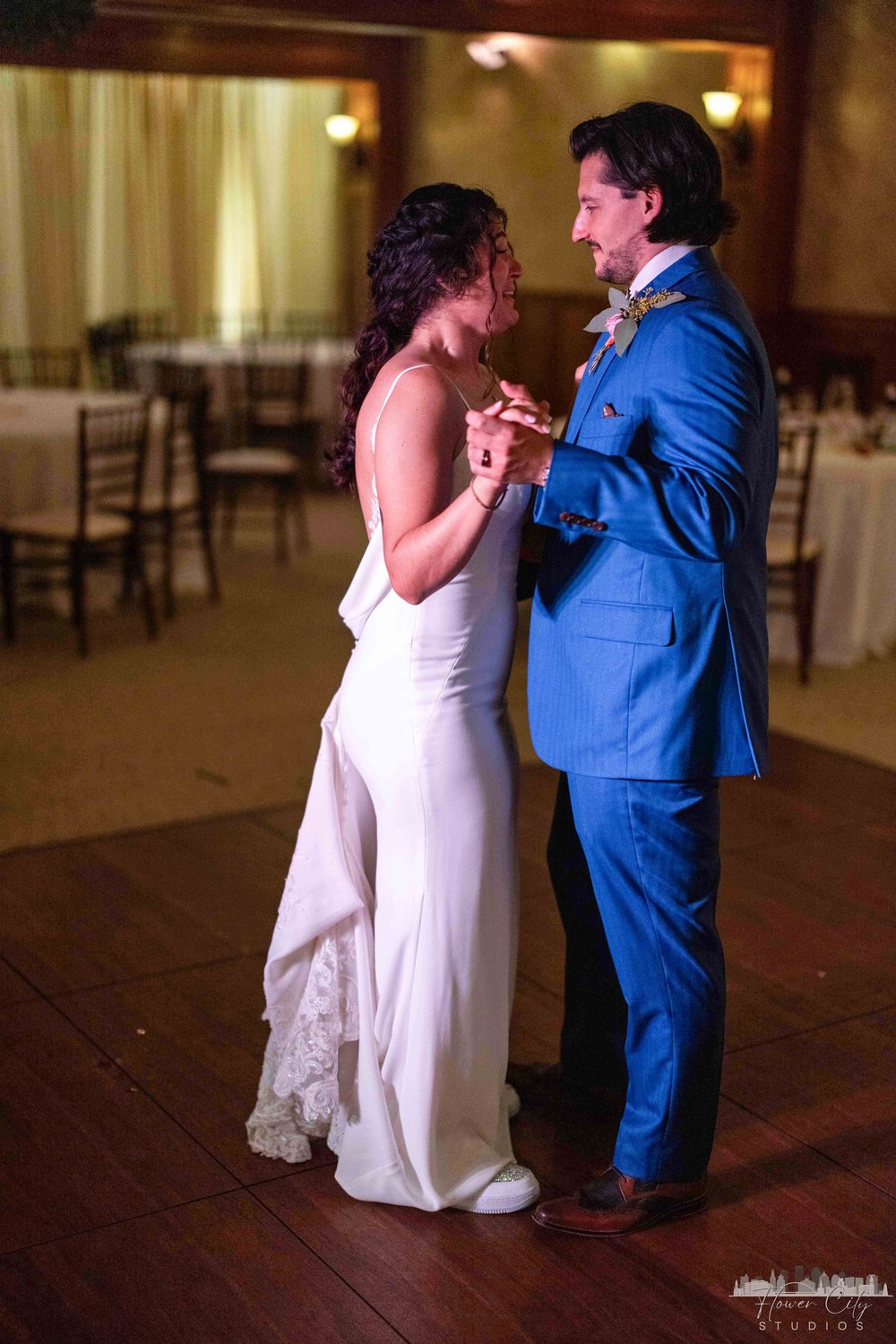 Bride and groom in a blue suit dancing on the reception floor