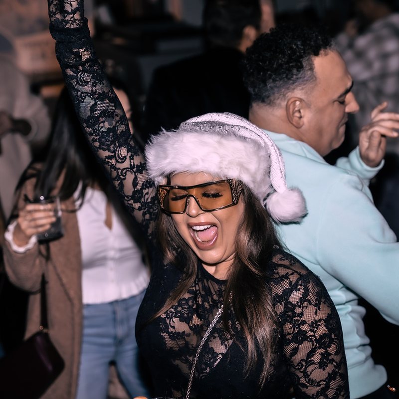 Birthday party guest in a Santa hat cheering on the dance floor