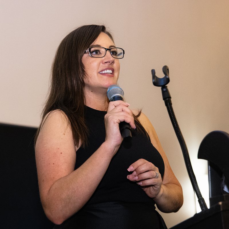 Speaker addressing the room with a microphone at a charity dinner