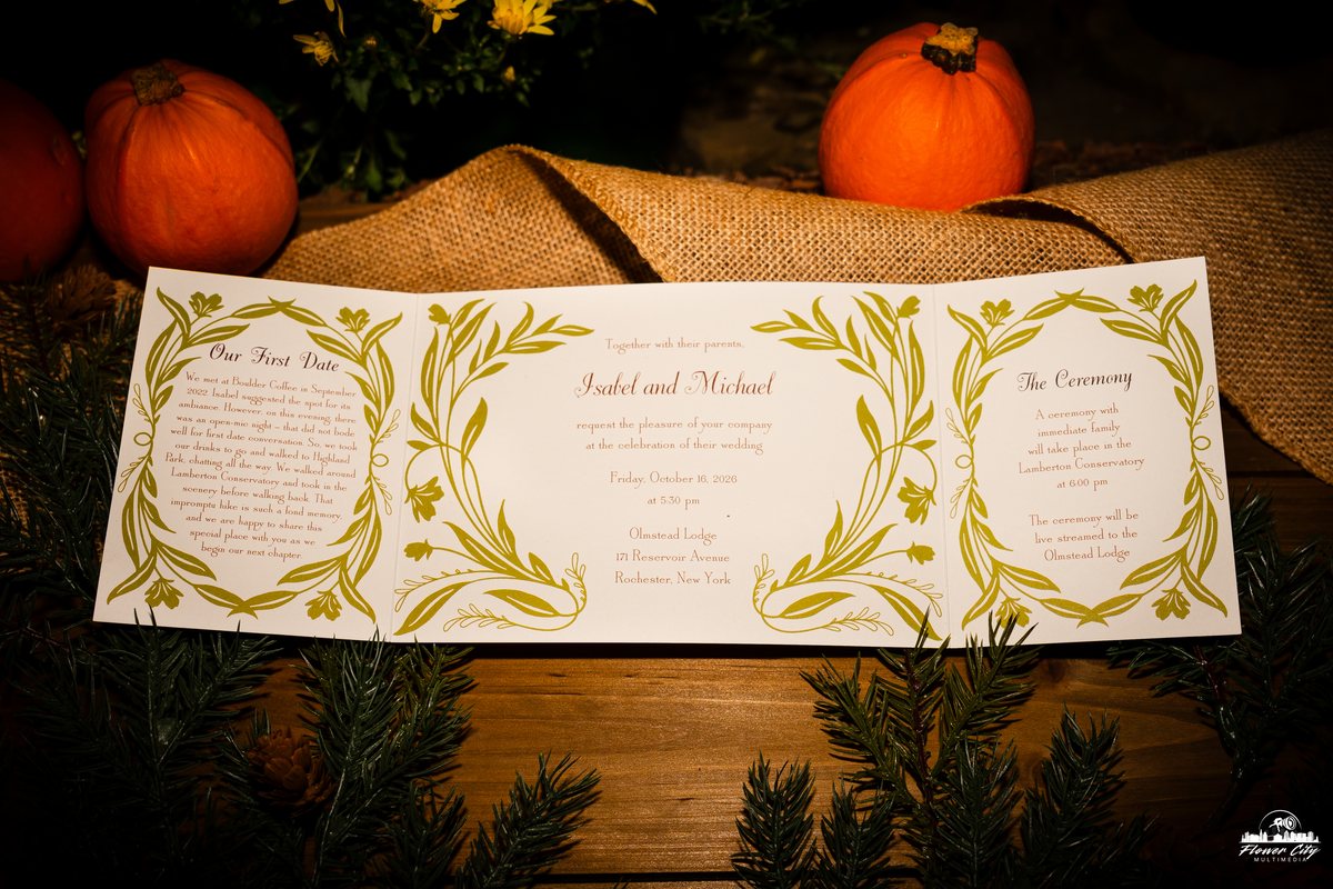 Letterpress-style wedding invitation suite displayed with autumn pumpkins