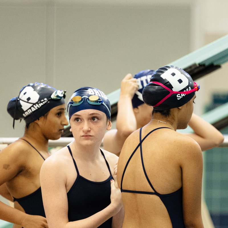 Swim teammates in team caps sharing a moment on deck before a race